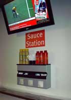 Sauce station model#01 (large napkins version) at the Emirates stadium, holding mustard and ketchup bottles with gravity fed sachet dispenser, plus forks in the cup