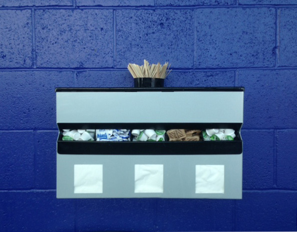 Wall Mouinted Saucestation at ACC Liverpool showing Stirrers dispenser at top with two cutlery trays, Condiment dispenser in the middle and napkin dispensers below.