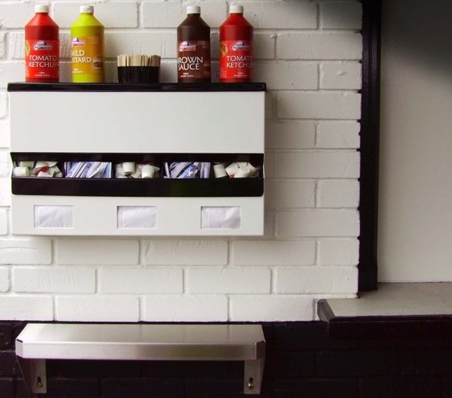Sauce Station at Fulham F.C's Stadium showing sauce bottle holder middle acrylic sachet dispenser in ABS plastic, and Napkin dispensers. An early Stainless Steel Saucing shelf sits below .