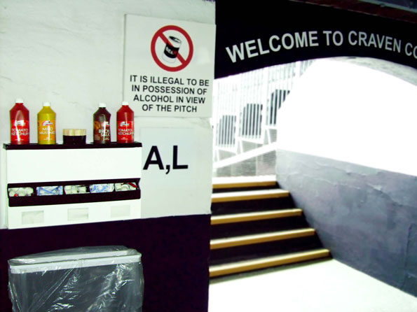 Sauce Station at Fulham F.C's Stadium showing sauce bottle holder middle acrylic sachet dispenser in ABS plastic, and Napkin dispensers. An early wall-mounted slim profile trash bag holder sits below
