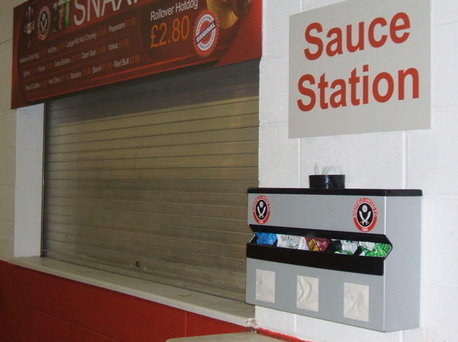 Sauce Station Condiment dispenser at Sheffield Utd's Bramhall Lane Stadium showing the unique combination of Sauce Bottle tray, Condiment sachet dispenser, and Napkin Dispenser combined with Cup for Straws or Stirrers
